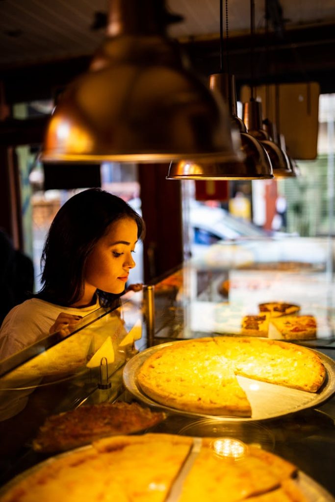 photo-of-woman-looking-at-pizza-2531110 A woman looks at delicious pizza options in a cozy São Paulo restaurant.